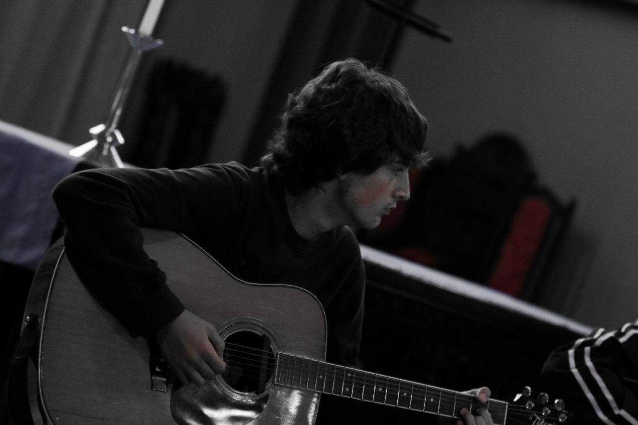 Max Thornhill playing acoustic guitar in a church