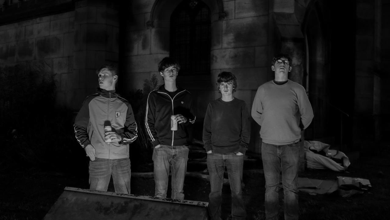 The Fleecers outside a church at night in black and white