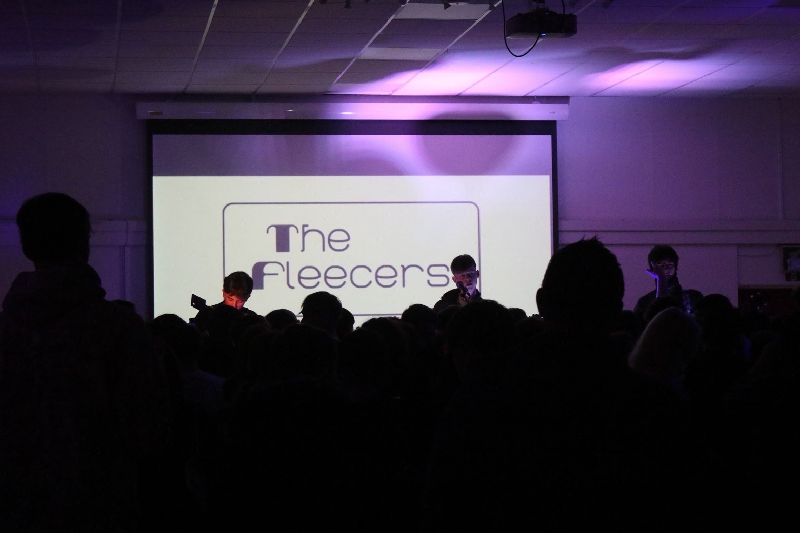The Fleecers on stage under the band's projected logo