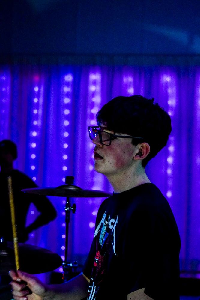James Lister of The Fleecers behind the drum kit under purple stage lights